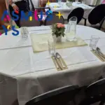 Megterített kerek asztal virággal és vizeskancsóval